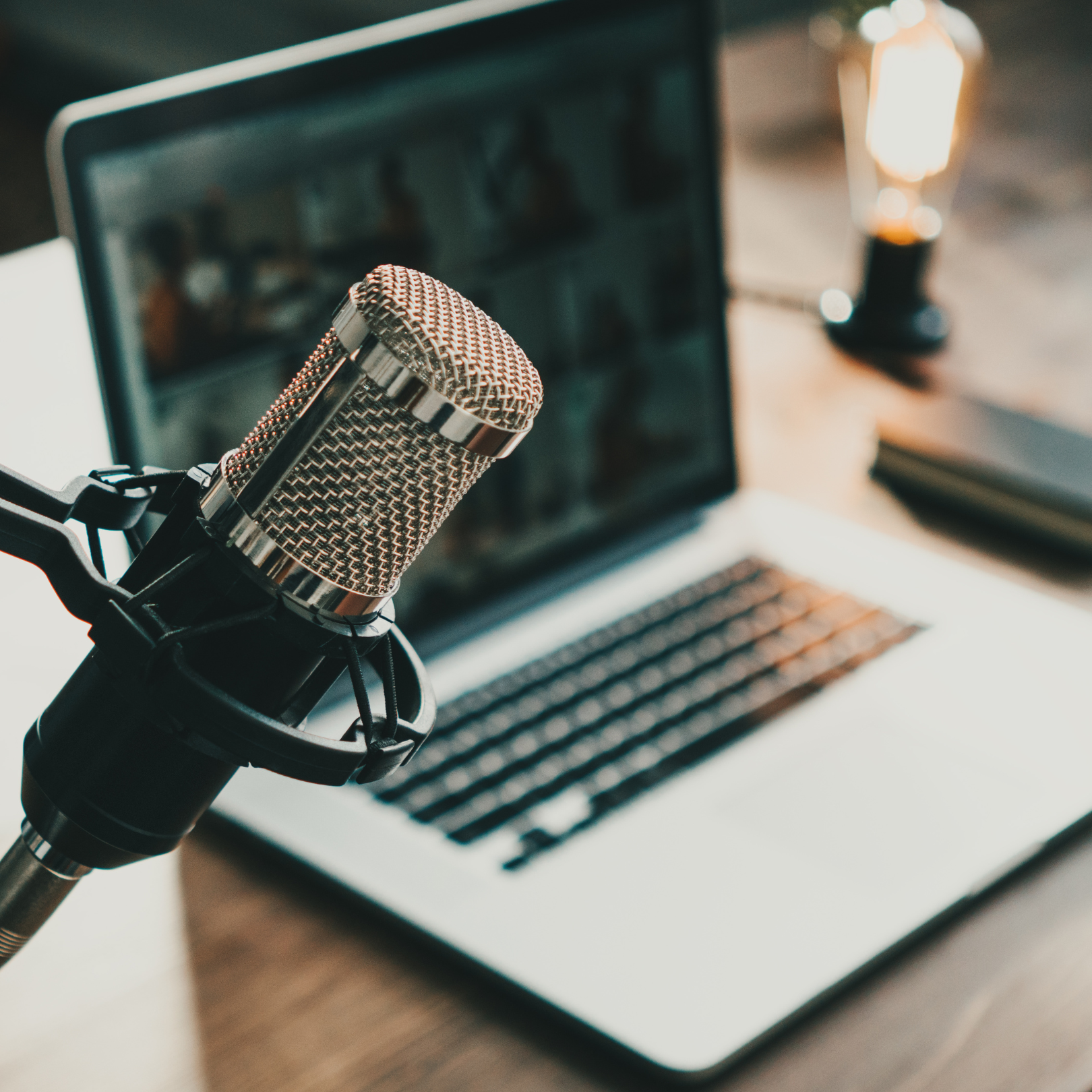 A podcast microphone and a laptop on a desk